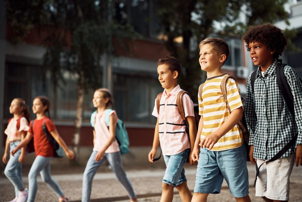 Multiracial group of happy elementary students coming to school.